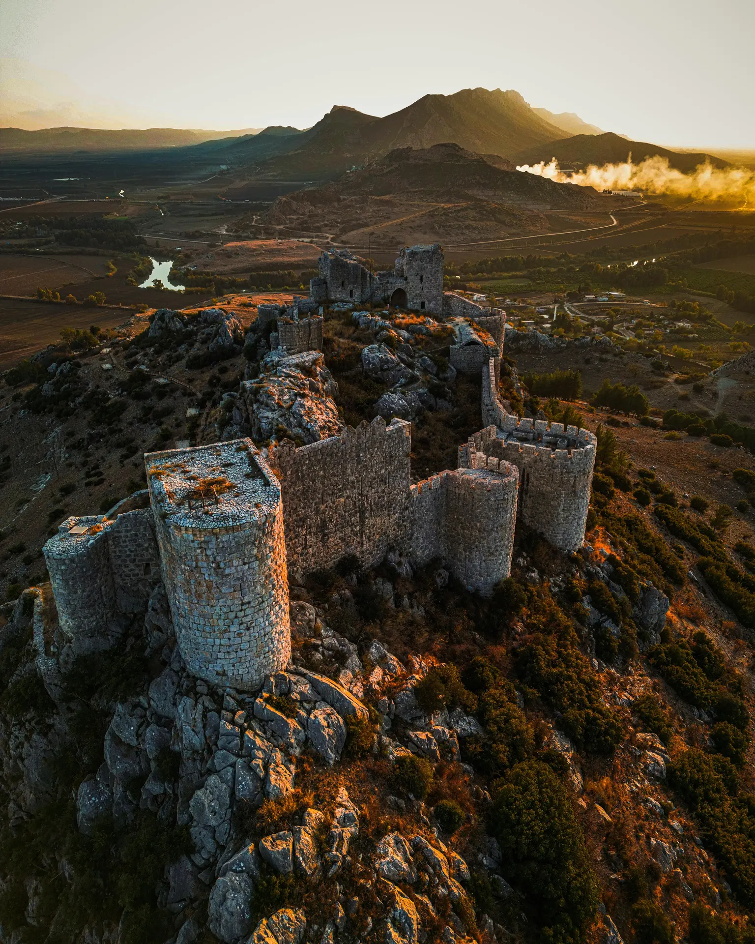 Camino rural seco junto a dehesa y fortaleza en Extremadura